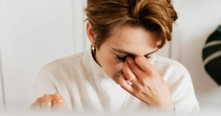 Exhausted woman pinching the bridge of her nose from constant fatigue