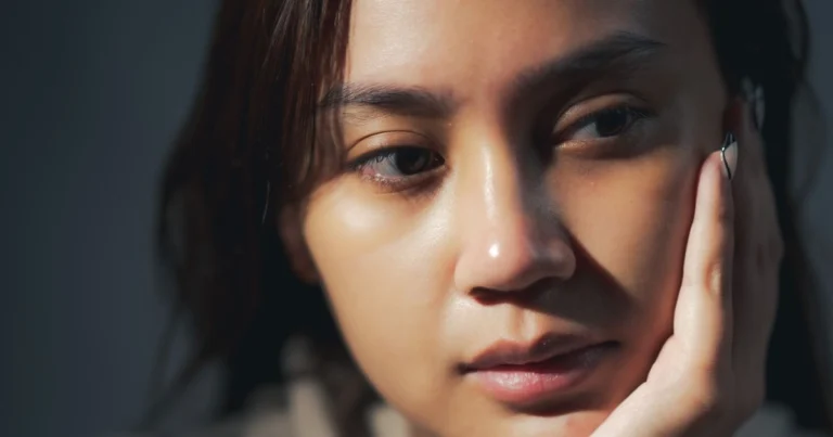 Woman with a pensive, thoughtful expression, resting her face in her hand
