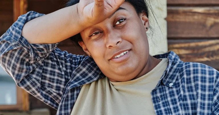 Woman wiping sweat from her forehead during a hot flash