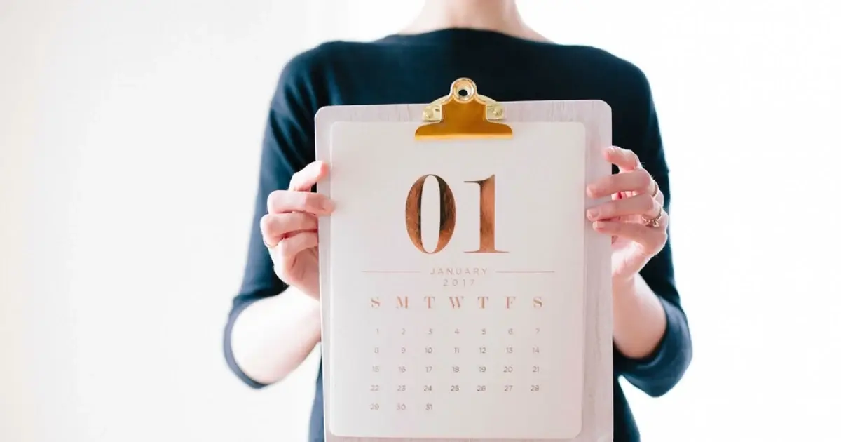 A woman holds up a calendar showing January 1st