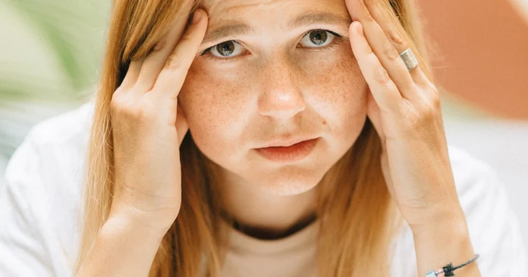 Woman pressing her temples, showing visible anxiety and tension