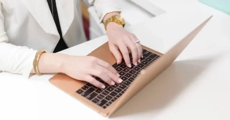 A woman types on a laptop at a desk