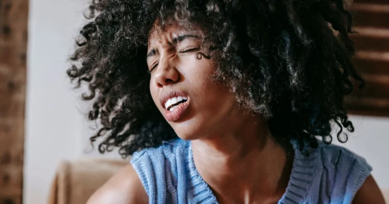 Woman wincing in discomfort, holding her stomach