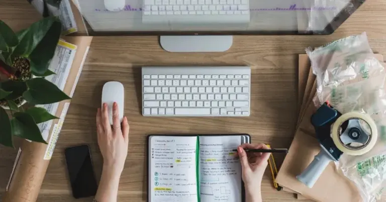 A desk with a laptop, an open notebook and a phone