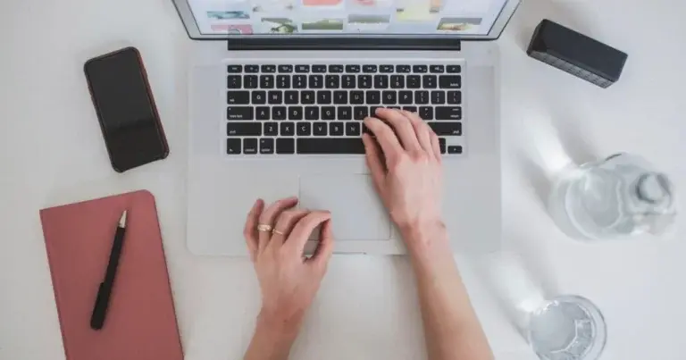 Hands typing on a laptop at a desk