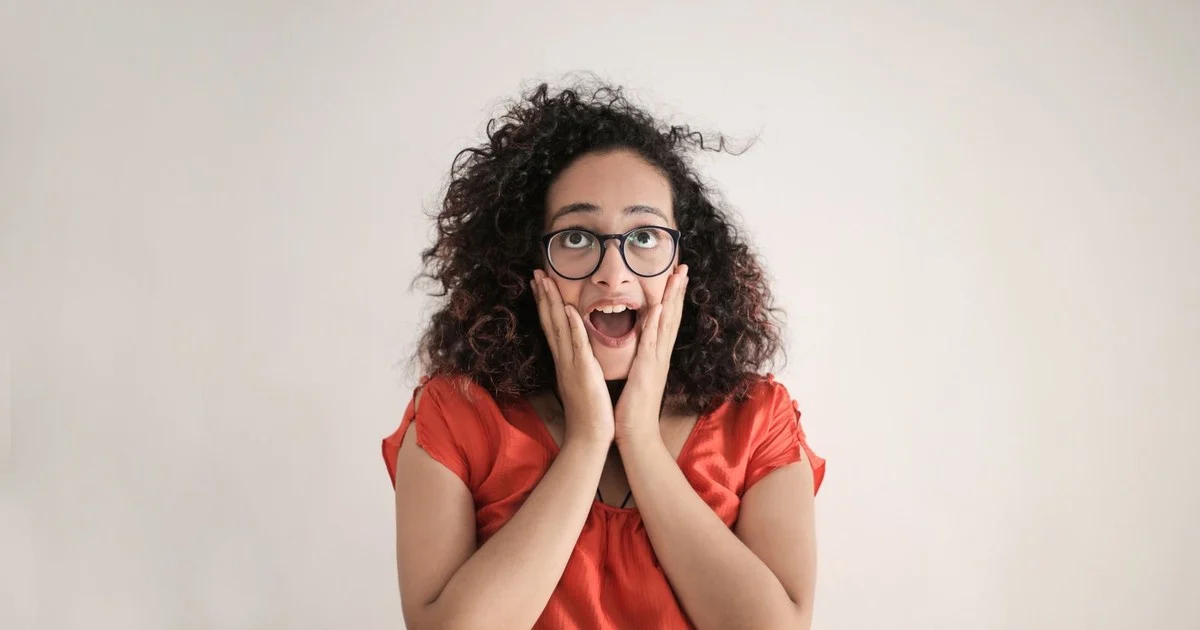 Surprised woman with her hands on her face, learning the difference between perimenopause and menopause