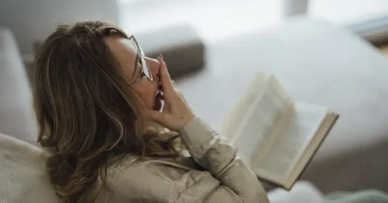 A woman relaxes on a couch reading a book