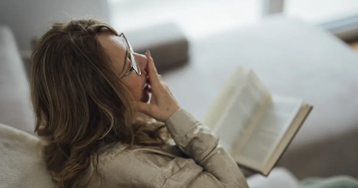 A woman relaxes on a couch reading a book
