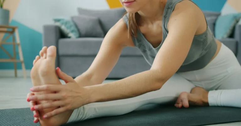 Woman doing a gentle seated stretch on a yoga mat at home