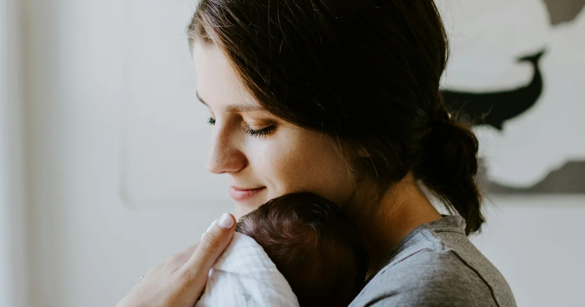 Mother holding her newborn close to her shoulder