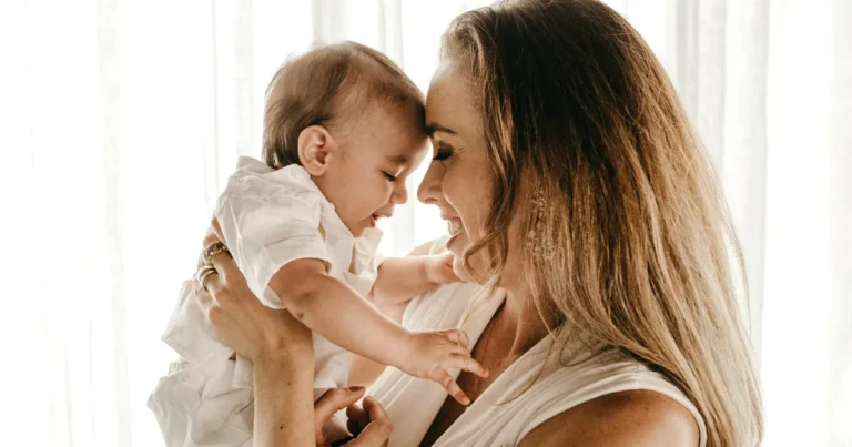 Smiling mother lifting her baby at home