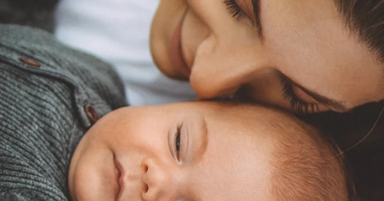 Mother resting her cheek against her sleeping baby